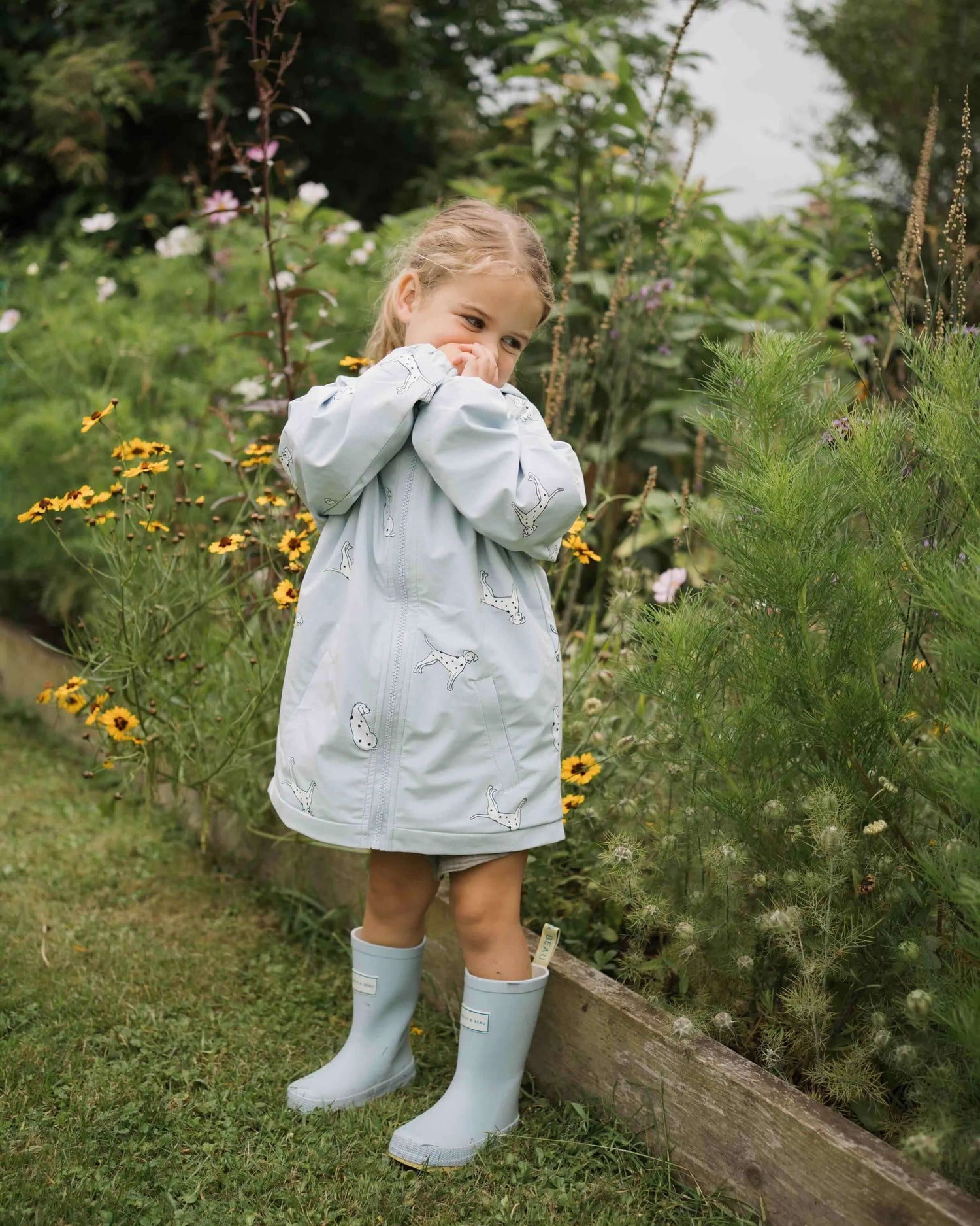 Holly and Beau Lifestyle of toddler girl in the garden wearing her dalmatian colour changing raincoat
