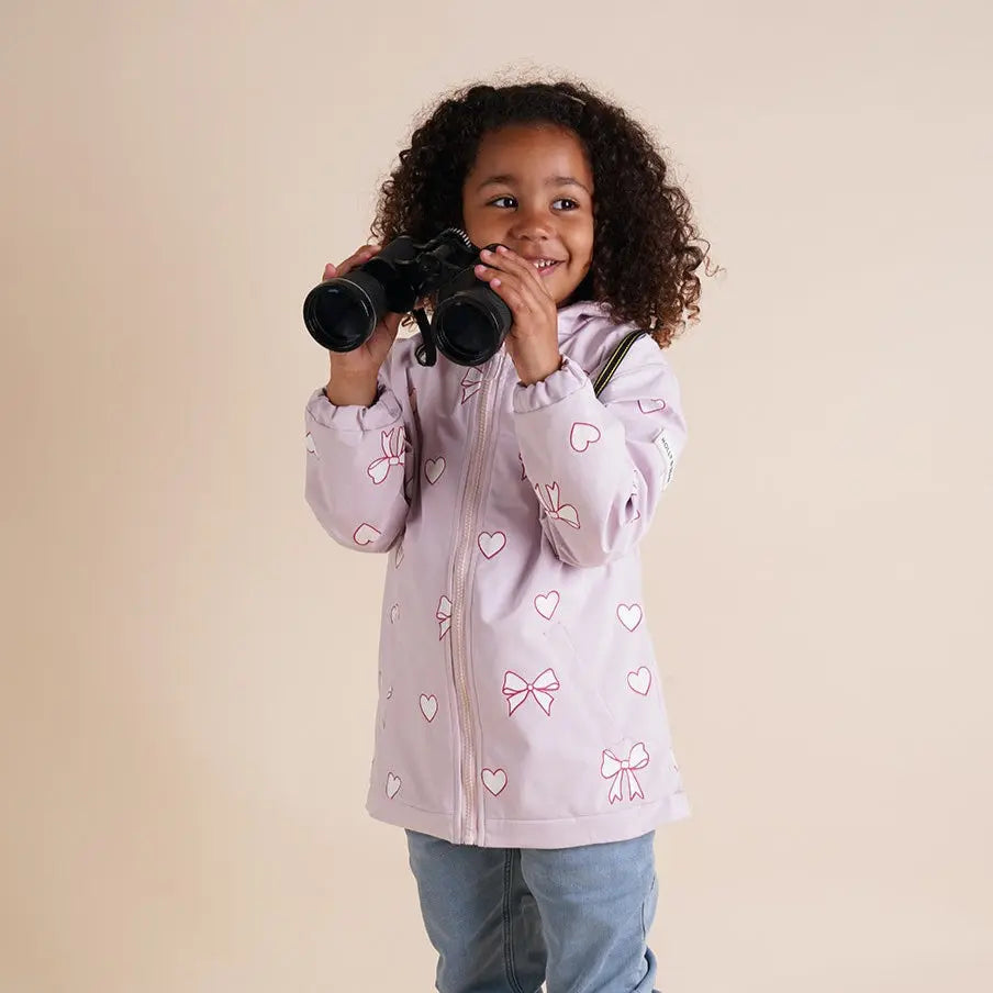 Girl smiling wearing the pink bows and hearts colour changing raincoat by Holly and Beau